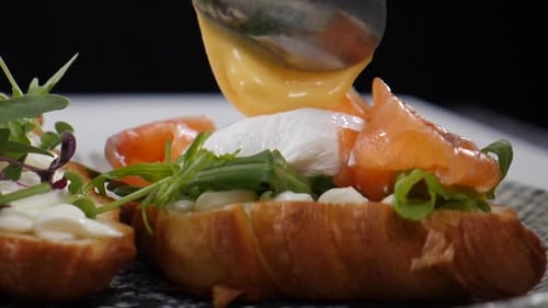 Serving Breakfast with Croissant Sandwich Green Salad and Tomato Being Poured with Cheese Sauce Slow