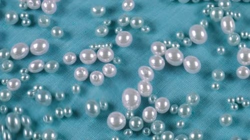 Pearls Falling onto Blue Textured Fabric