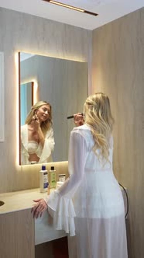 Woman Applies Makeup in Modern Bathroom by Mirror