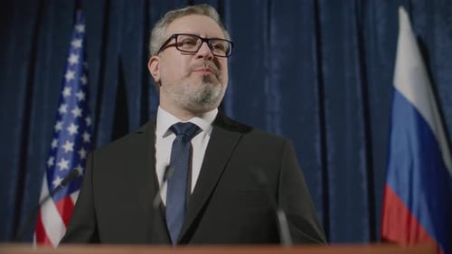 Man Speaks at Podium with Flags