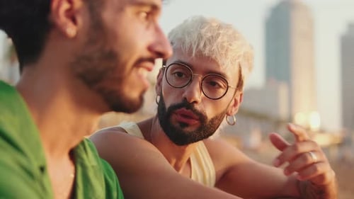 De perto, casal homossexual apaixonado passa tempo juntos sentados na praia ao nascer do sol