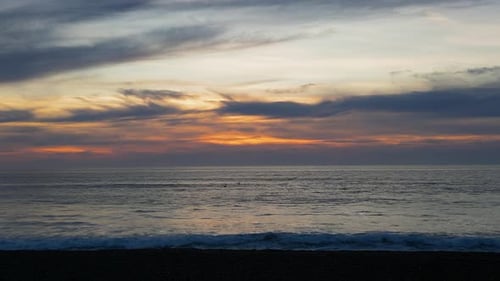 4K Drone footage of sunset over the ocean with birds waves and clouds.