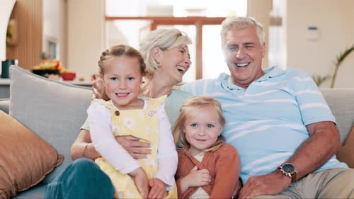 Grandparents Cuddling with Granddaughters on Couch at Home