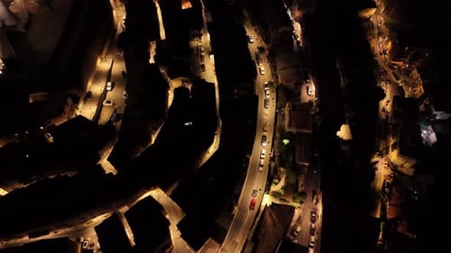Aerial night view of winding city streets illuminated by streetlights