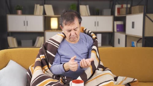 Man Massaging Sore Hands on Couch Indoors