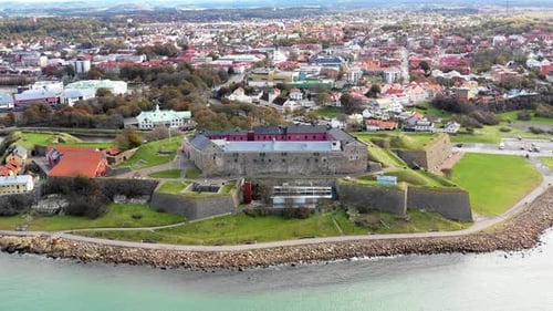 Aerial view of old fortress by the ocean. Town in background. CIRCLING COUNTER CLOCKWISE.