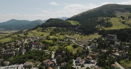 Aerial view of hillside town with winding roads, Italy.