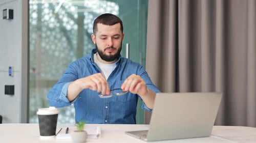 Satisfied Professional Removing Glasses At Modern Office Desk