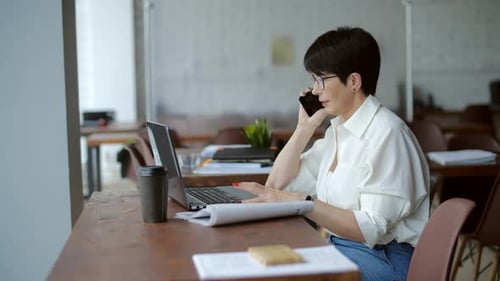 Elderly Businesswoman Working in Modern Office Making Phone Call to Potential Client Having Nice