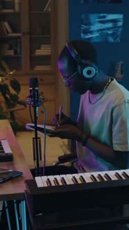 Musician Writing Notes and Preparing Mic at Home Recording Studio