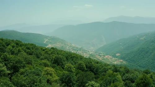 Drohnenaufnahmen einer grünen Berglandschaft mit einem Dorf — 4K-Luftaufnahme