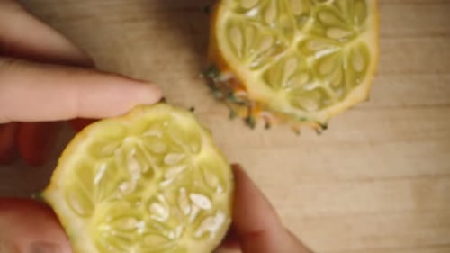 A top-down view of me scooping out the flesh and seeds from a halved Kiwano cucumber. Macro