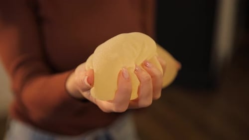 Woman Holding Silicone Breast Implants in Hands