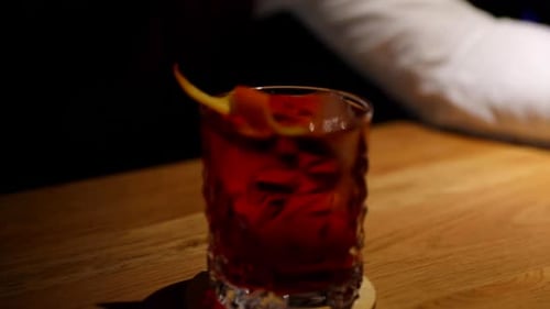 Close up zoom out of moving bartender with fresh finished alcoholic drink ready to serve to customer