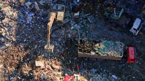 Excavator Loading Garbage Truck at Landfill