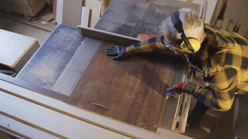 Adult carpenter are using table saw to cut in carpentry shop.