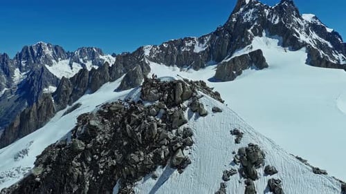 Bergsteiger erklimmen erfolgreich einen verschneiten Kamm in einem riesigen Alpenmassiv