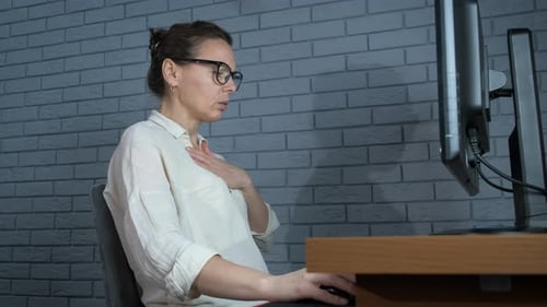 Woman Using Inhaler at Desk in Office