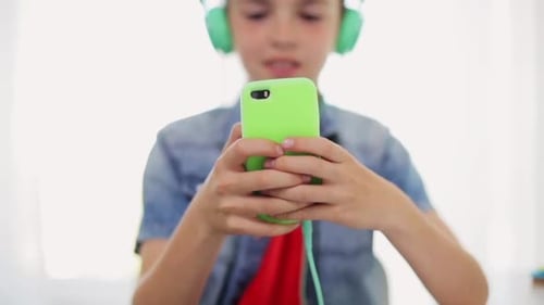 Child Wearing Headphones Holds Phone