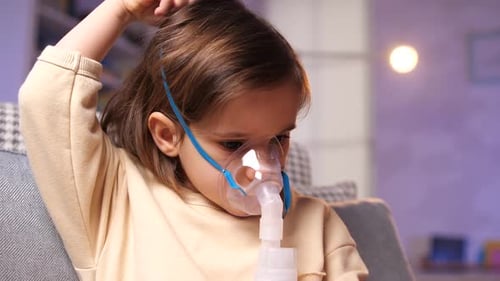 Child With Oxygen Mask Sitting in Chair