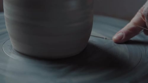 Potter travaille et coupe également l'argile supplémentaire à l'aide de la ficelle