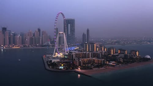 Eye of Dubai ferris wheel aerial view at night with JBR beach and skyscrapers in the background