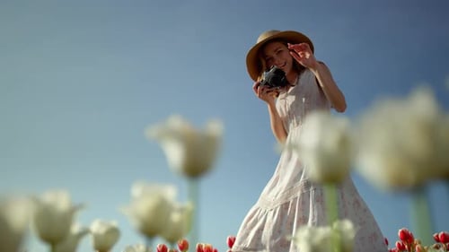 Playful Woman Taking Pictures of Spring Flowers on Blue Sky Background. Beautiful