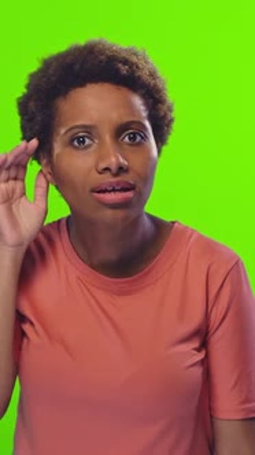 Femme écoutant attentivement sur fond vert vif en studio