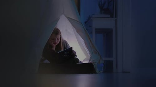 Girl Reading Book Inside Tent at Night