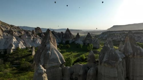 Aerial view of colorful hot air balloons fly in the sky over a mountain valley in Cappadocia