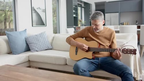 Man Plays Guitar on Couch in Living Room