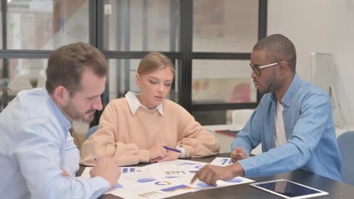 Business Team Discusses Charts and Graphs in Office