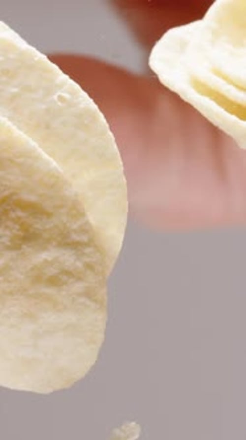 Vertical video. Corn chips in the shape of a saddle, view from below through a glass table.