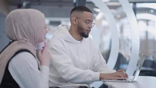 In a Modern Office Setting an African American Businessman and His Muslim Colleague Wearing a Hijab