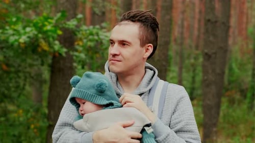 Young Father with His Newborn Baby in a Sling Walking in the Autumn Forest The Concept of a Happy