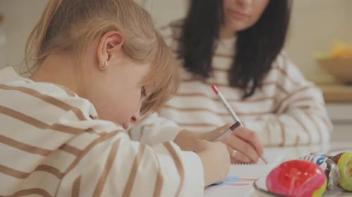 Child Draws at Table Indoors With Adult