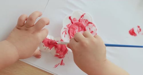 Infant Painting With a Brush and Red Paint