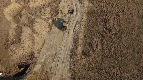 Aerial View of a Yellow Tractor That Performs Earthworks on a Dirt Road