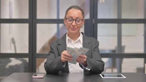 Mixed Race Business Woman Counting Money in Office