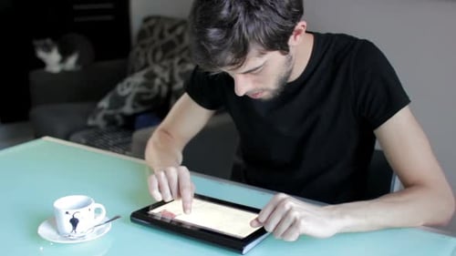 Male college student using tablet computer and having coffee
