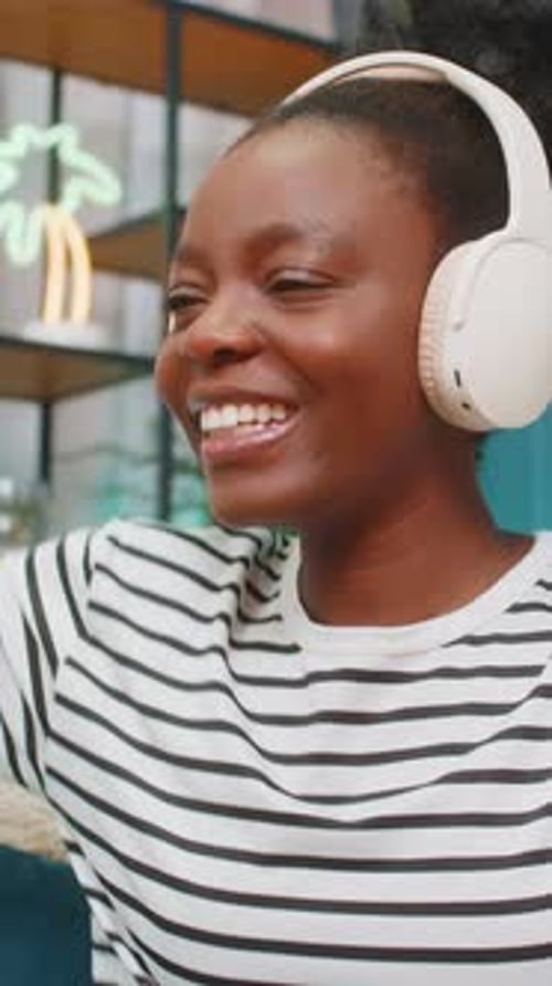 Smiling Woman Listens to Music with Headphones