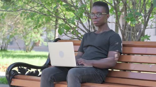 Young Man Works on Laptop in Park