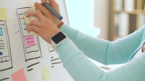 Woman Designing App on Whiteboard in Modern Office