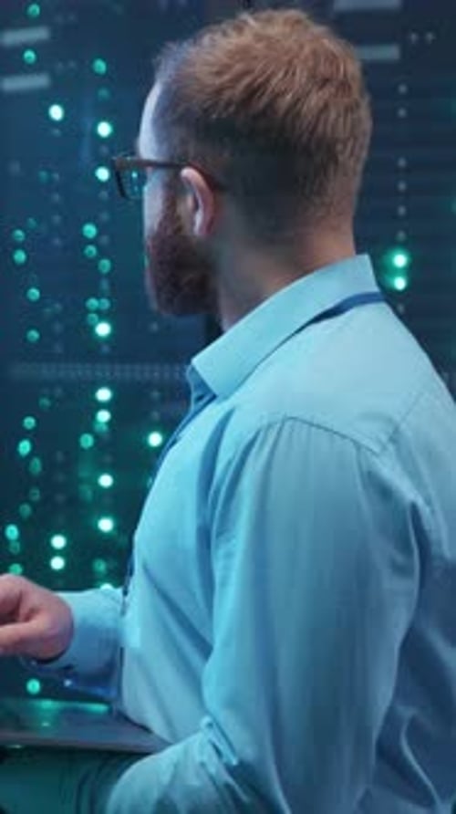 A Skilled Tech Professional Working Diligently in a Data Center While Using His Laptop