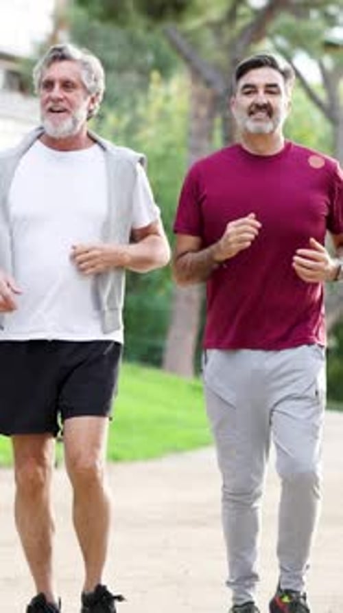 Two Mature Men Friends Jogging Together in a Park Vertical