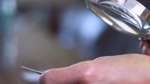 Woman Inspecting Object with Magnifying Glass Close Up