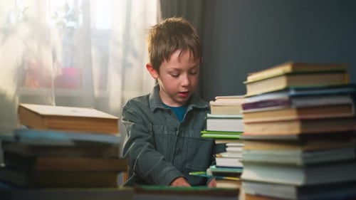 Boy Reading Among Stacked Books at Table
