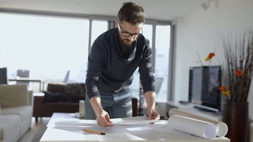 Man reviewing architectural plans in modern apartment