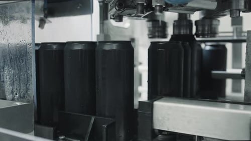 Black aluminum cans moving on conveyor belt in factory