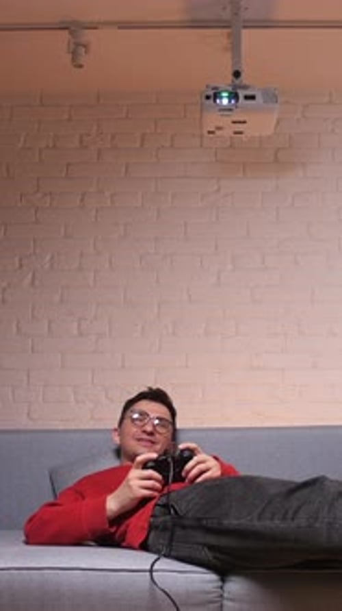 Man Playing Video Game on Couch Using Projector